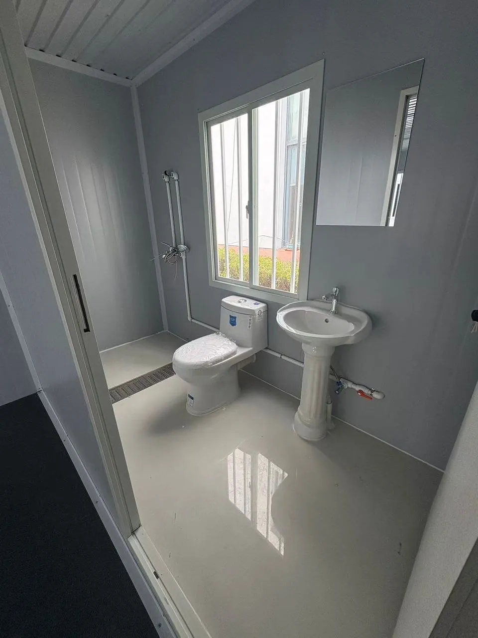 Baño alargado con ventana, inodoro y lavamanos